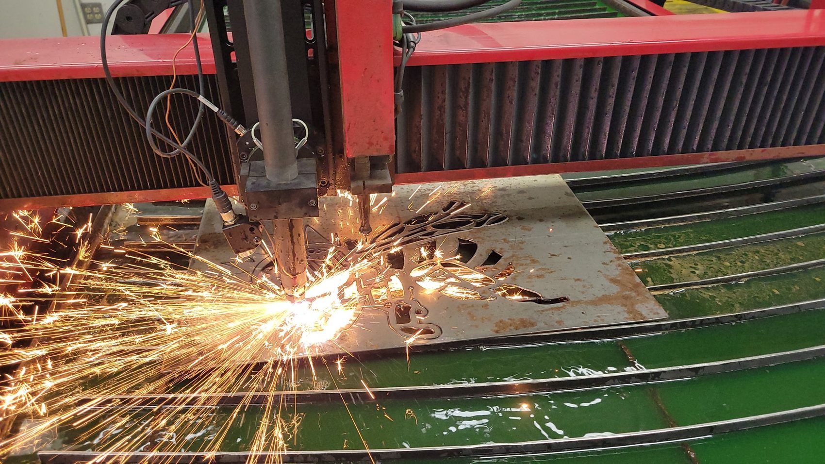 Plasma cutter carving a bee silhouette out of raw steel plate on the CNC table