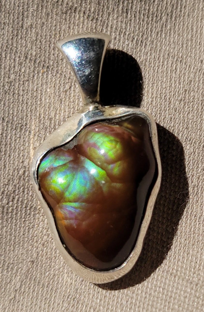 Freeform iridescent stone pendant set in a hand-fabricated sterling silver bezel
